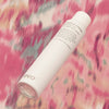 Eine Dose Shebang-A-Bang Dry Spray Wax schwebt vor rosa gemusterten Stoffhintergrund.