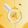 Eine runde Flasche Haarsirup-Honigtau-Öl tropft mit Honig, während eine Biene in der Nähe fliegt, vor einem gelben Hintergrund.