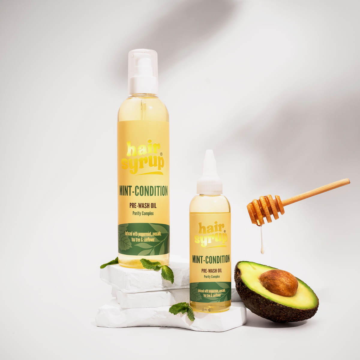Zwei Flaschen Hair Syrup Mint Condition Öl mit Avocado, Honigdip und Minze sind auf weißem Hintergrund abgebildet.