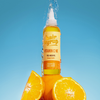 Eine Flasche Hair Syrup Vitamin C Me-Öl mit Sprühwasser, umgeben von frischen Orangenscheiben.