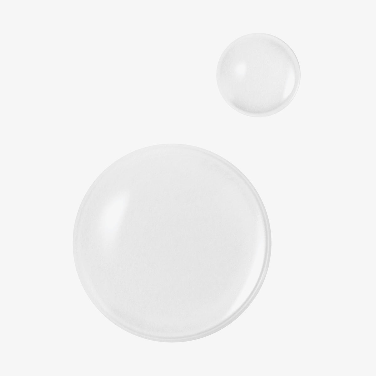 Auf weißem Hintergrund sind zwei klare Tropfen Real Complexion Hyaluron Skin Essence zu sehen.