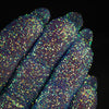 Nahaufnahme von mit Glitter Pot Mermaid Fin überzogenen Fingern mit funkelndem blau-grünem Glitzer.