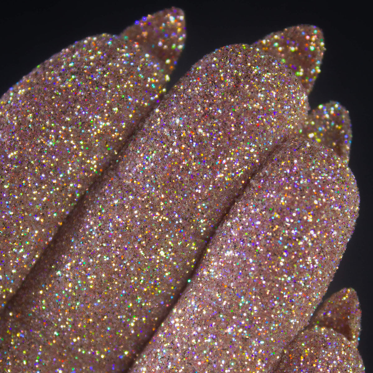 Nahaufnahme von mit Glitter Pot Mrs Rose überzogenen Fingern mit funkelndem rosa-goldenem Glitzer.
