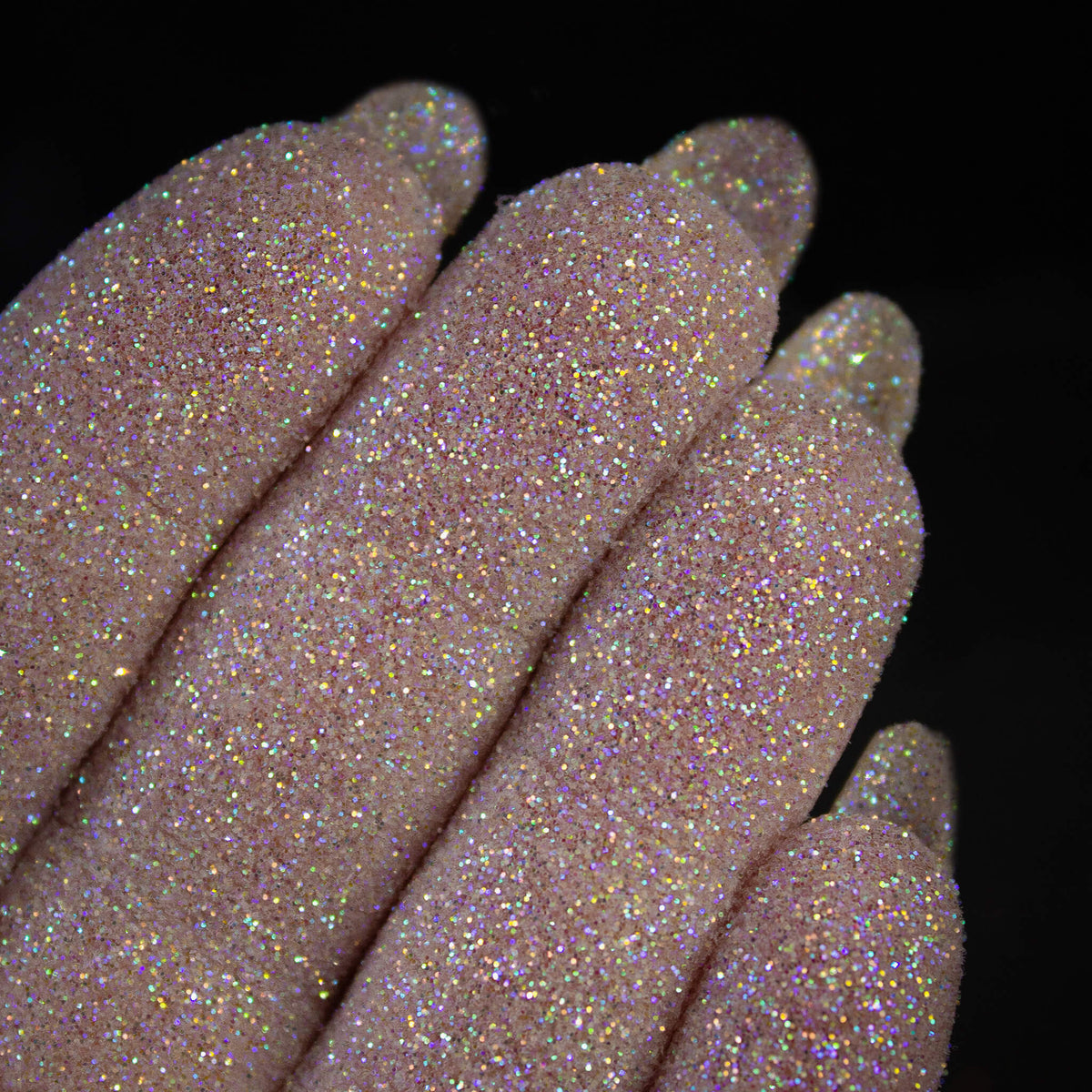 Nahaufnahme von mit Glitter Pot Pixie Magic überzogenen Fingern mit funkelndem weiß-silber und buntem Glitzer.