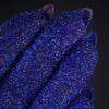 Nahaufnahme von mit Glitter Pot Sapphire Gem überzogenen Fingern mit funkelndem blau-lilanem Glitzer.