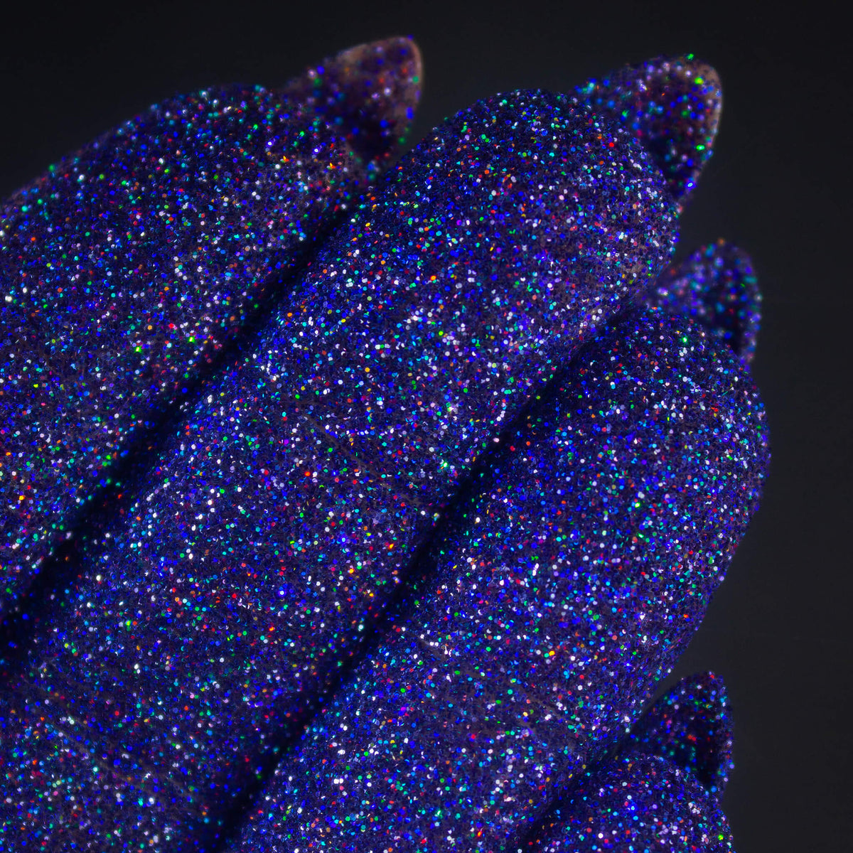 Nahaufnahme von mit Glitter Pot Sapphire Gem überzogenen Fingern mit funkelndem blau-lilanem Glitzer.