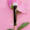 Nahaufnahme des K20: Small Oval Shader von Karla Cosmetics vor einem verschwommenen rosa Blumenhintergrund.