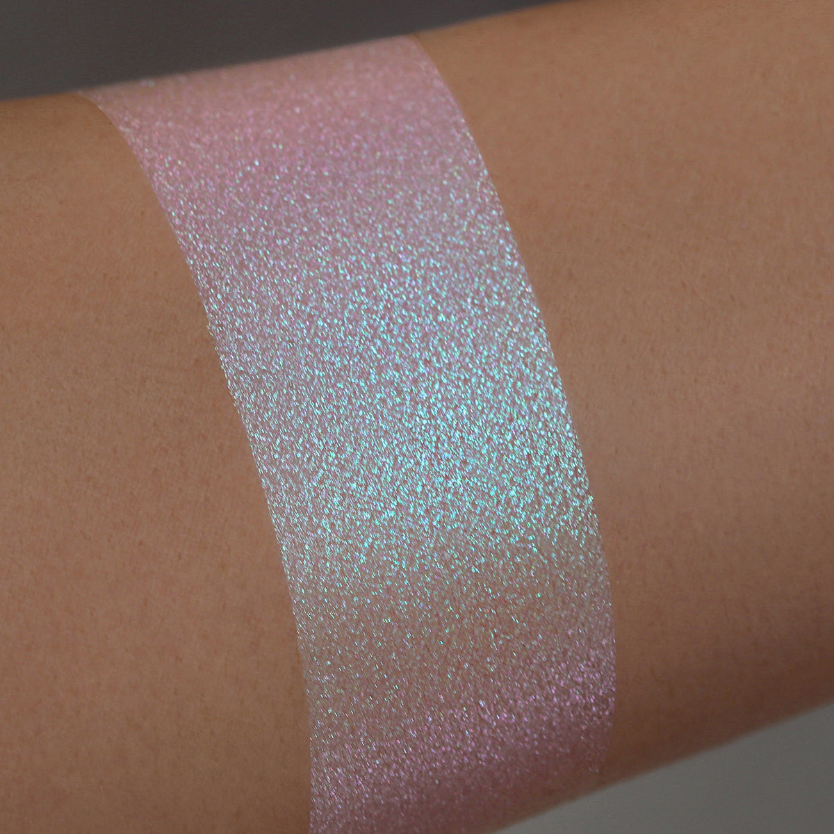 Ein schimmernder, schillernder rosa-blauer Farbstreifen Opal Multichrome Loose Eyeshadow Bubble Bath auf einem Arm.