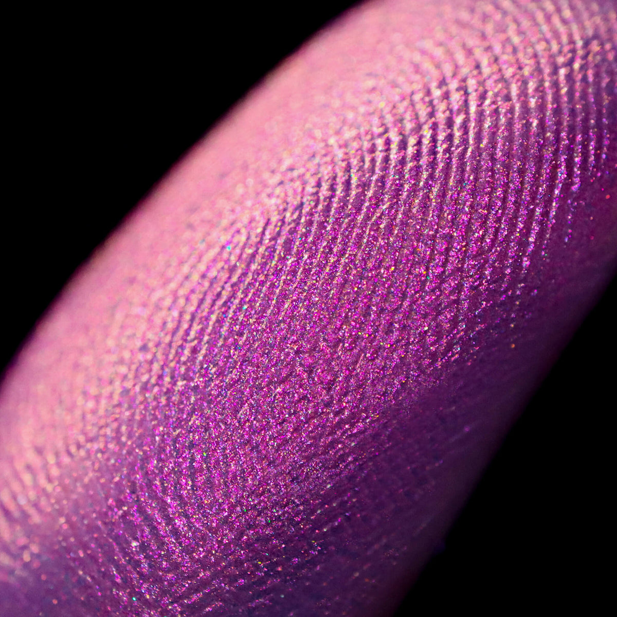 Nahaufnahme einer Fingerspitze, die in den Pastel Duochromes Loose Eyeshadow Blossom getaucht wurde und pink glitzert.