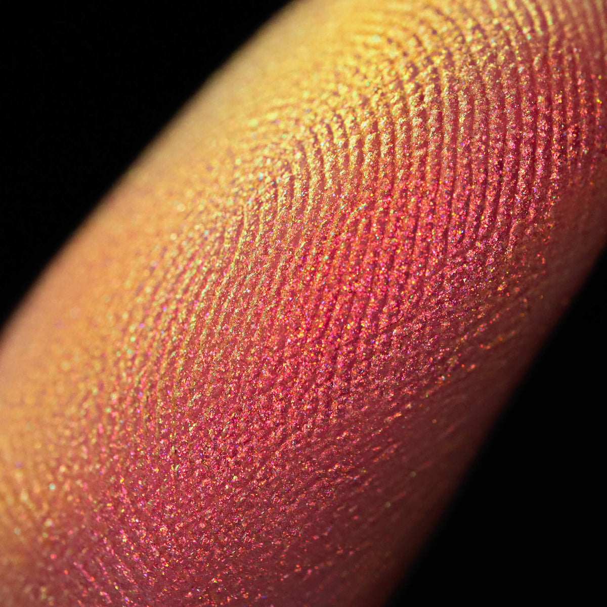 Nahaufnahme einer Fingerspitze, die in den Pastel Duochromes Loose Eyeshadow Sherbet getaucht wurde und gelb und orange glitzert.