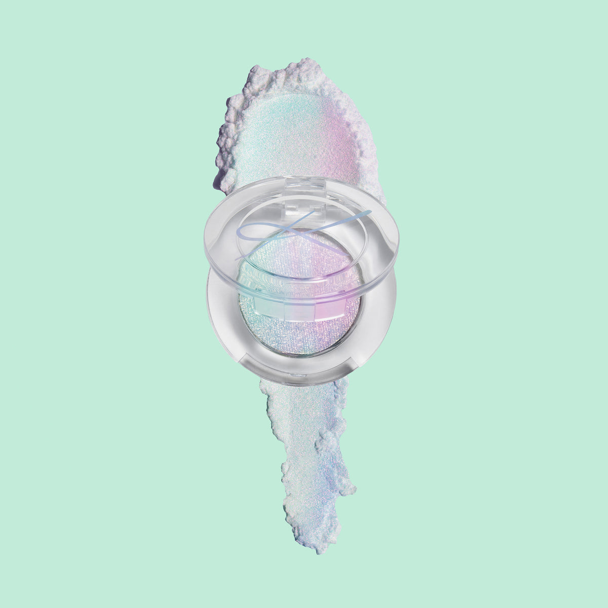 Kompaktdose des Pressed Opal Multichrome Eyeshadow Rockabye Baby auf einem blau-lila opal-schimmerndem Farbmuster auf blassgrünem Hintergrund.