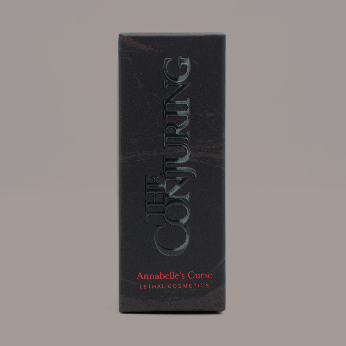 Eine schwarze Schachtel mit der Aufschrift „The Conjuring Matte Lipsticks by Lethal Cosmetics“ in roter Schrift auf grauem Hintergrund.