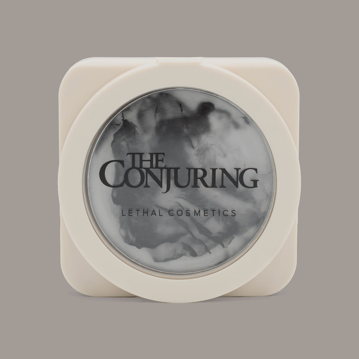 Ein runder, kompakter Behälter mit der Aufschrift „The Conjuring Sanctified Seal“ von Lethal Cosmetics, dessen Inhalt aus schwarz-weiß marmoriertem Puder besteht.