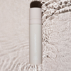 Beige Flasche LH Cosmetics On Set – Long Lasting Setting Spray auf einer Wasserfläche.