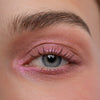 Nahaufnahme eines Auges zeigt einen kreativen rosa glitzernden Eyeliner, der mit dem Crayon Nunki von LH Cosmetics kreiert wurde.