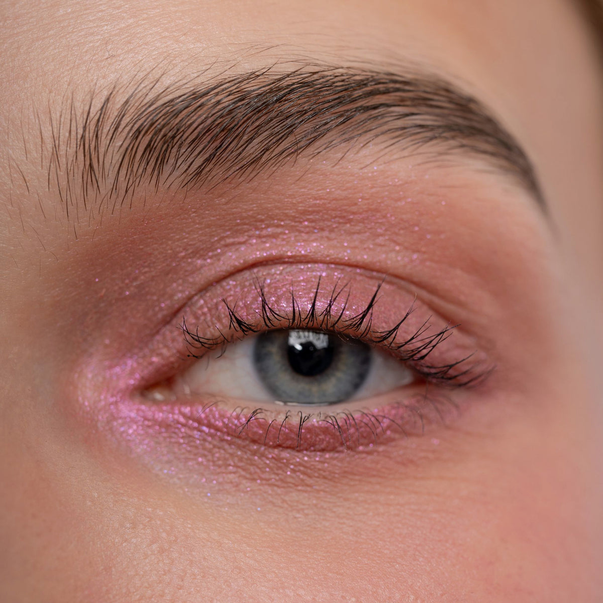 Nahaufnahme eines Auges zeigt einen kreativen rosa glitzernden Eyeliner, der mit dem Crayon Nunki von LH Cosmetics kreiert wurde.