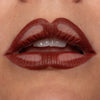 Nahaufnahme geschminkter Lippen mit braunem Lippenstift und bewusst ausgesparten Stellen, die ein verspieltes, grafisches Muster ergeben.
