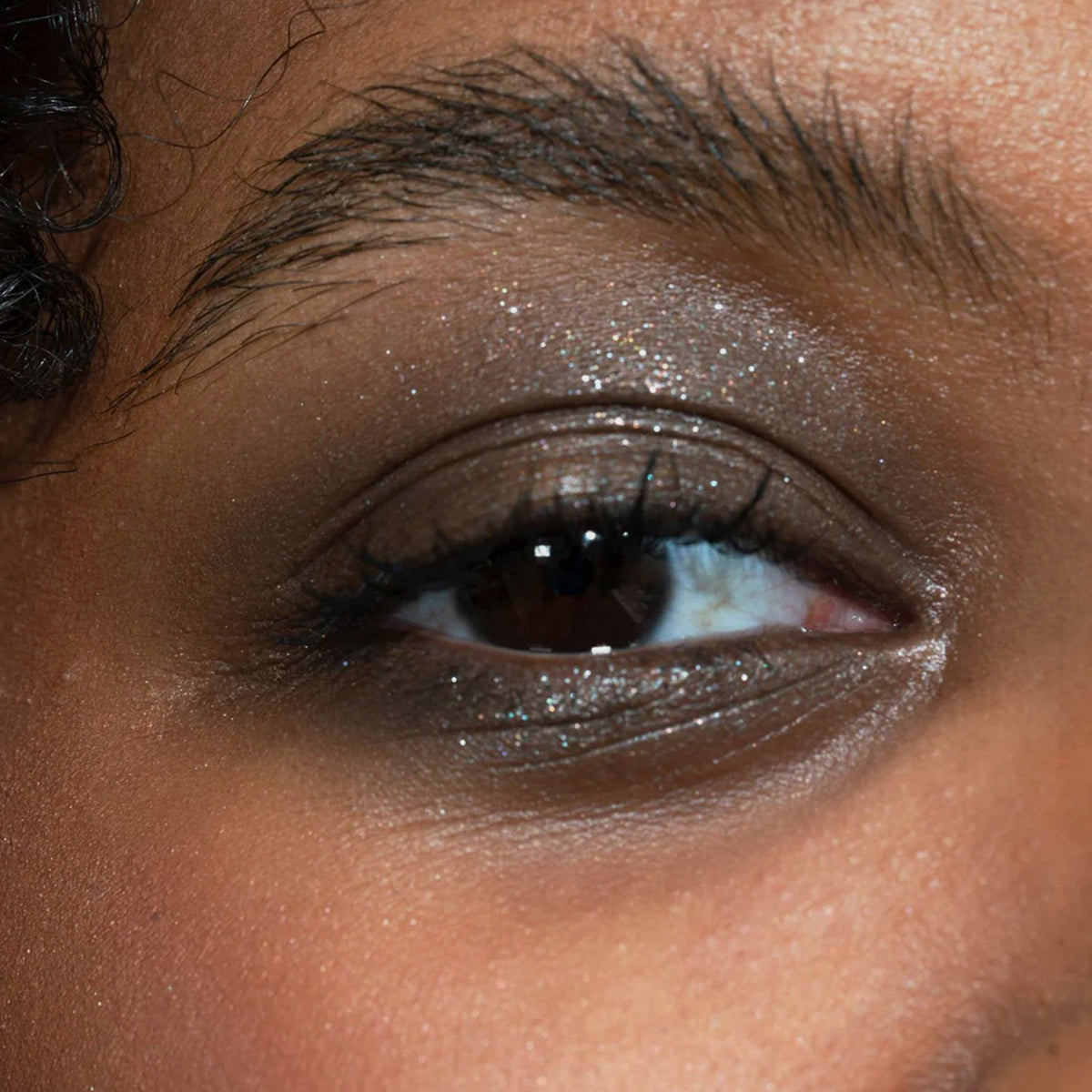 Nahaufnahme eines Auges zeigt einen kreativen braun glitzerndem Make-up-Look, der mit dem Crayon Saiph von LH Cosmetics kreiert wurde.