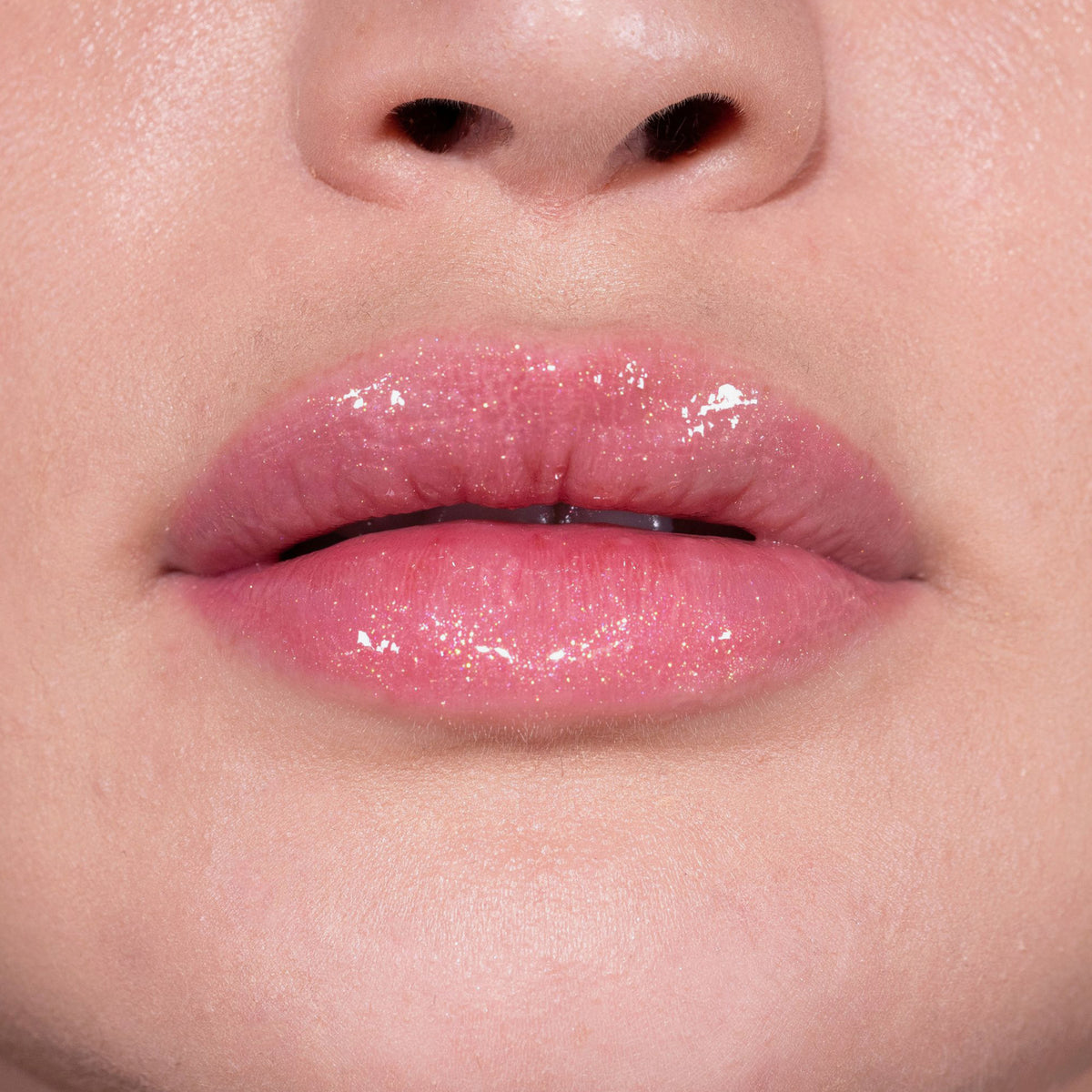 Nahaufnahme von Lippen einer Person mit hellem Teint mit transparentem glitzerndem Glazed Drip Lipgloss von LH Cosmetics.