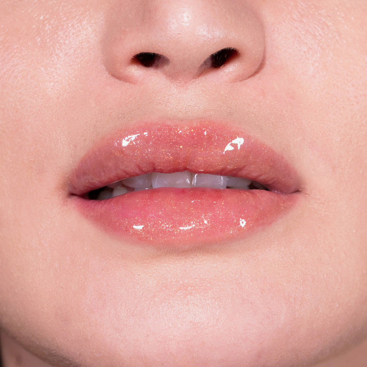 Nahaufnahme von Lippen einer Person mit hellem Teint mit leicht orange glitzerndem Glazed Melt Lipgloss von LH Cosemtics.