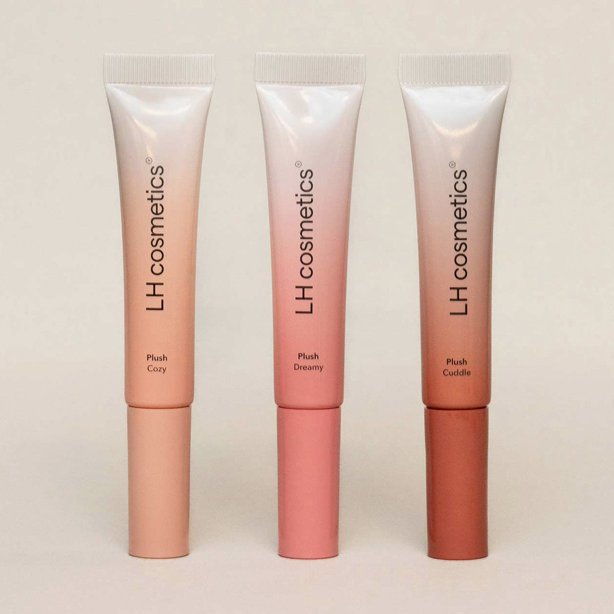 Drei Tuben der des LH Cosmetics Plush in den Farben „Cozy“, „Dreamy“ und „Cuddle“ auf beigem Hintergrund.