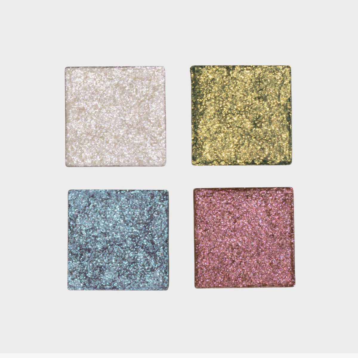 Vier Pfännchen der Siren Song Palette von LH Cosmetics mit glitzernden Lidschatten in Weiß, Gold, Blau und Pink vor einem hellen Hintergrund.