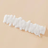 Gewelltes weißes Muster der Living Proof Curl Definer-Creme auf einer hellbeigen Oberfläche.