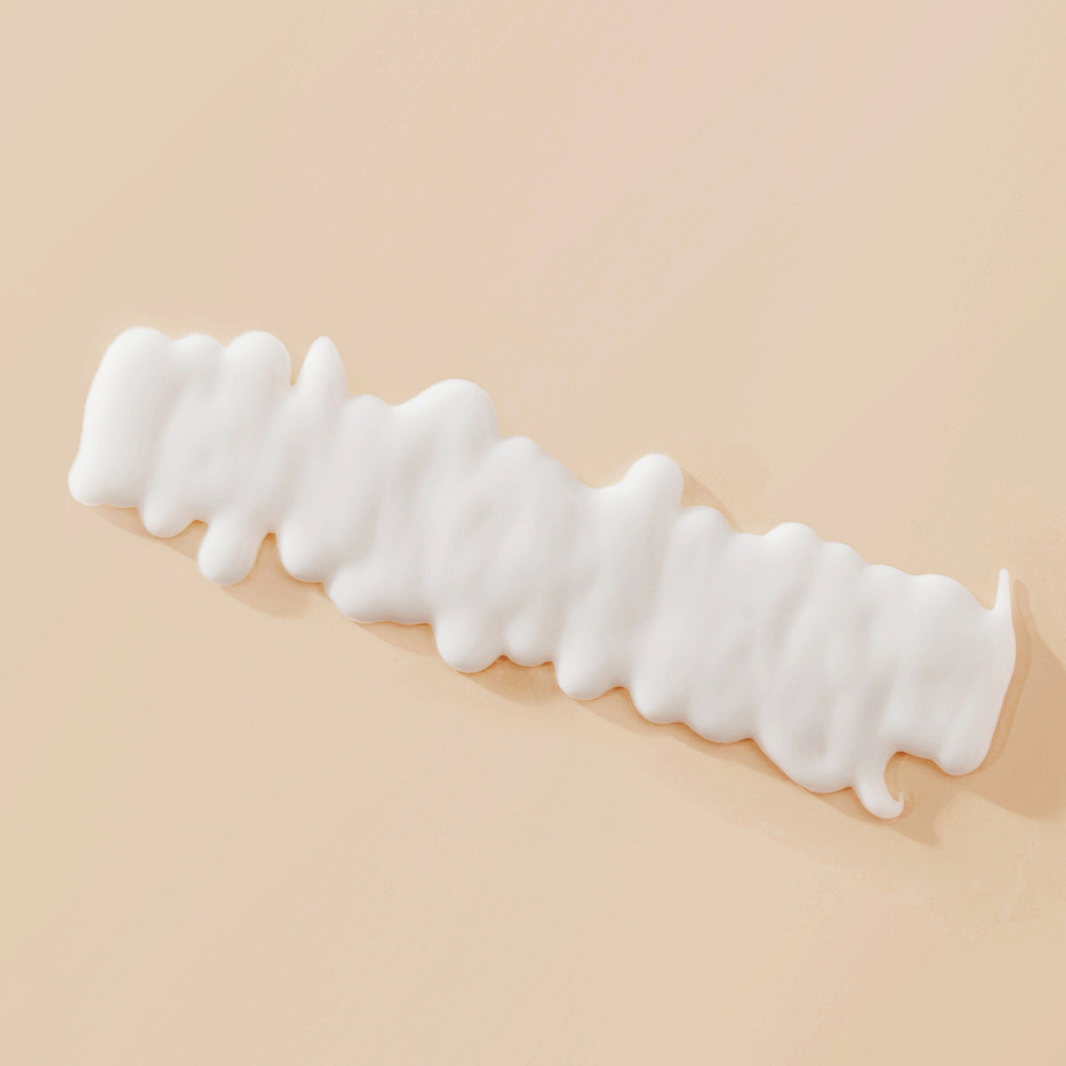 Gewelltes weißes Muster der Living Proof Curl Definer-Creme auf einer hellbeigen Oberfläche.