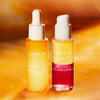 Zwei Flaschen des Lumene NORDIC-C [VALO] Essence + Oil-Cocktail Duo Set auf orangem Hintergrund.