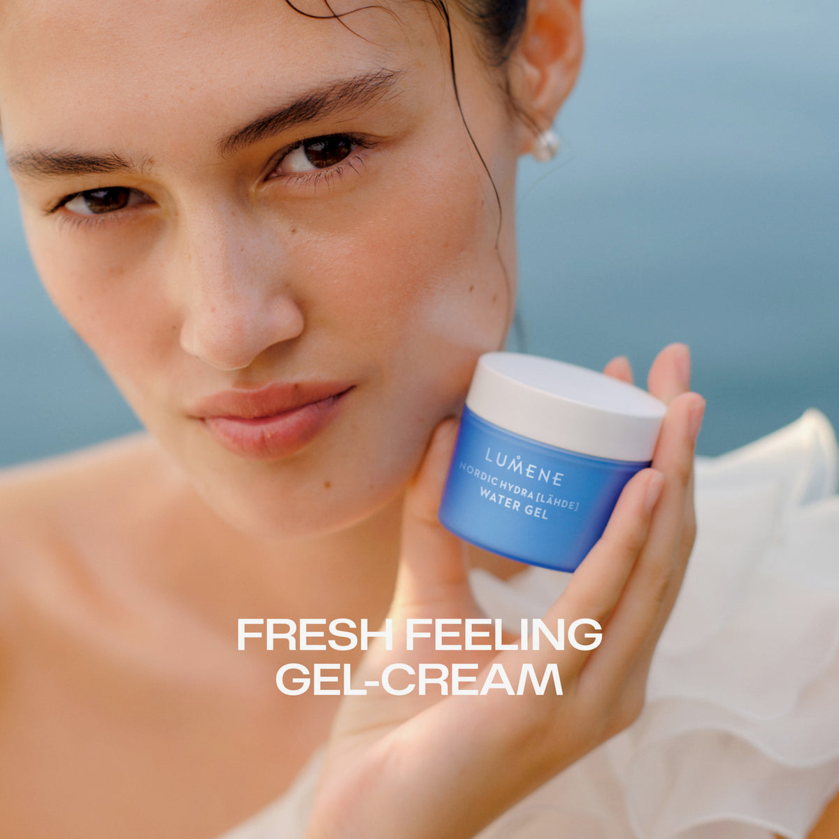 Frau hält einen Tiegel Lumene Nordic Hydra [LÄHDE] Water Gel mit dem Text "Fresh Feeling Gel-Cream" in der Hand.