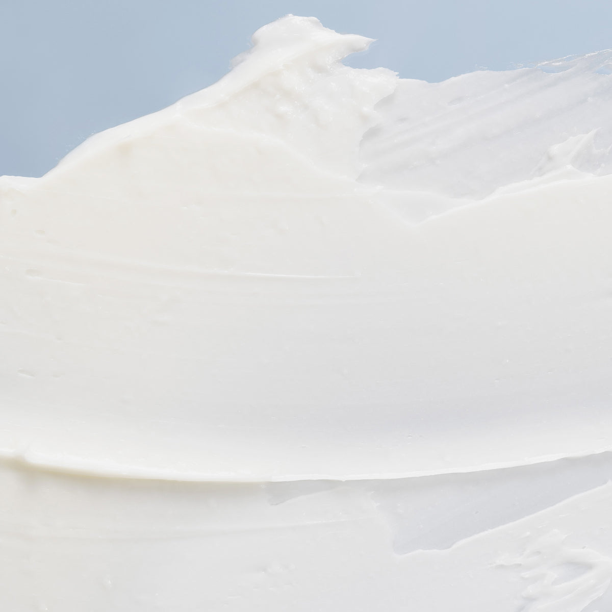 Weiße Creme-Textur der NORDIC SENSITIVE [HERKKÄ] Rich Day Cream auf einem hellblauen Hintergrund verteilt.