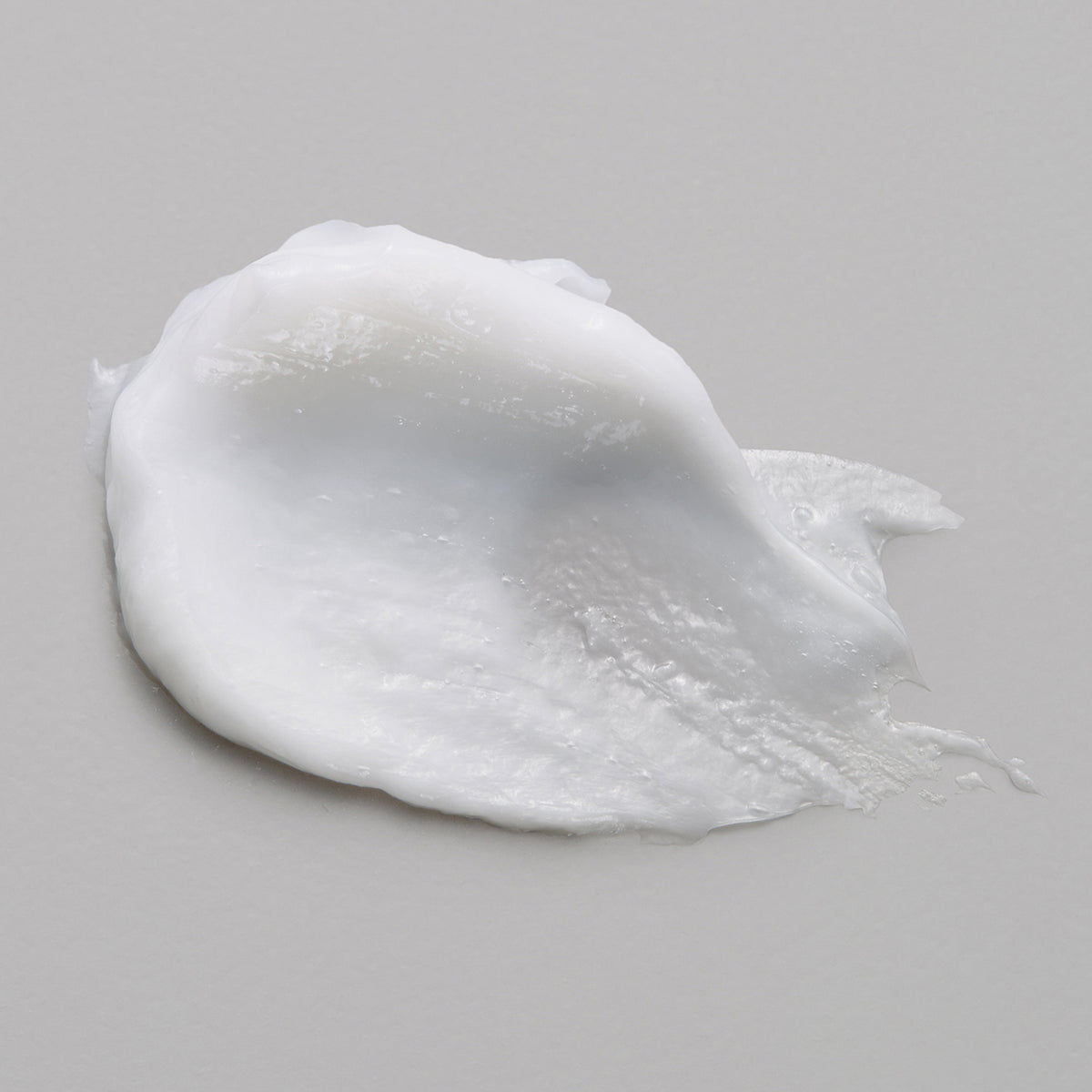 Ein weißer Klecks der maria nila Head & Hair Heal Masque auf einer hellgrauen Oberfläche.