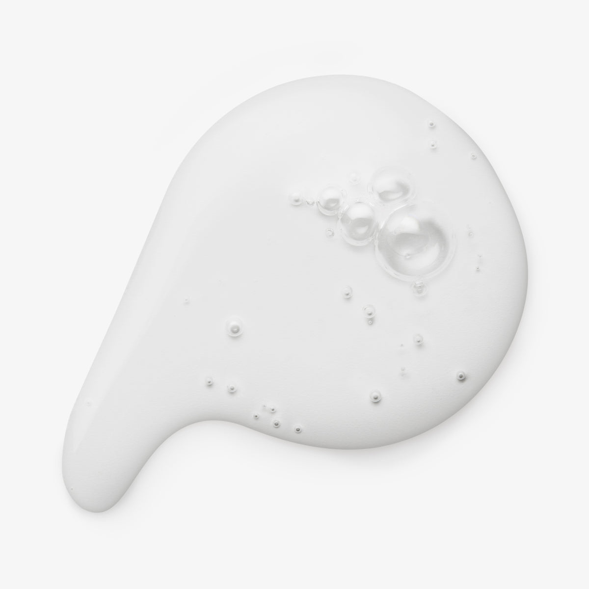 Klarer Tropfen des maria nila Purifying Cleanse Exfoliating Serum mit Bläschen auf weißem Hintergrund.
