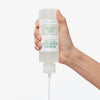 Eine Hand drückt die Flasche des Mario Badescu Acne Facial Cleanser zusammen und gibt den Reiniger aus der Düse frei.