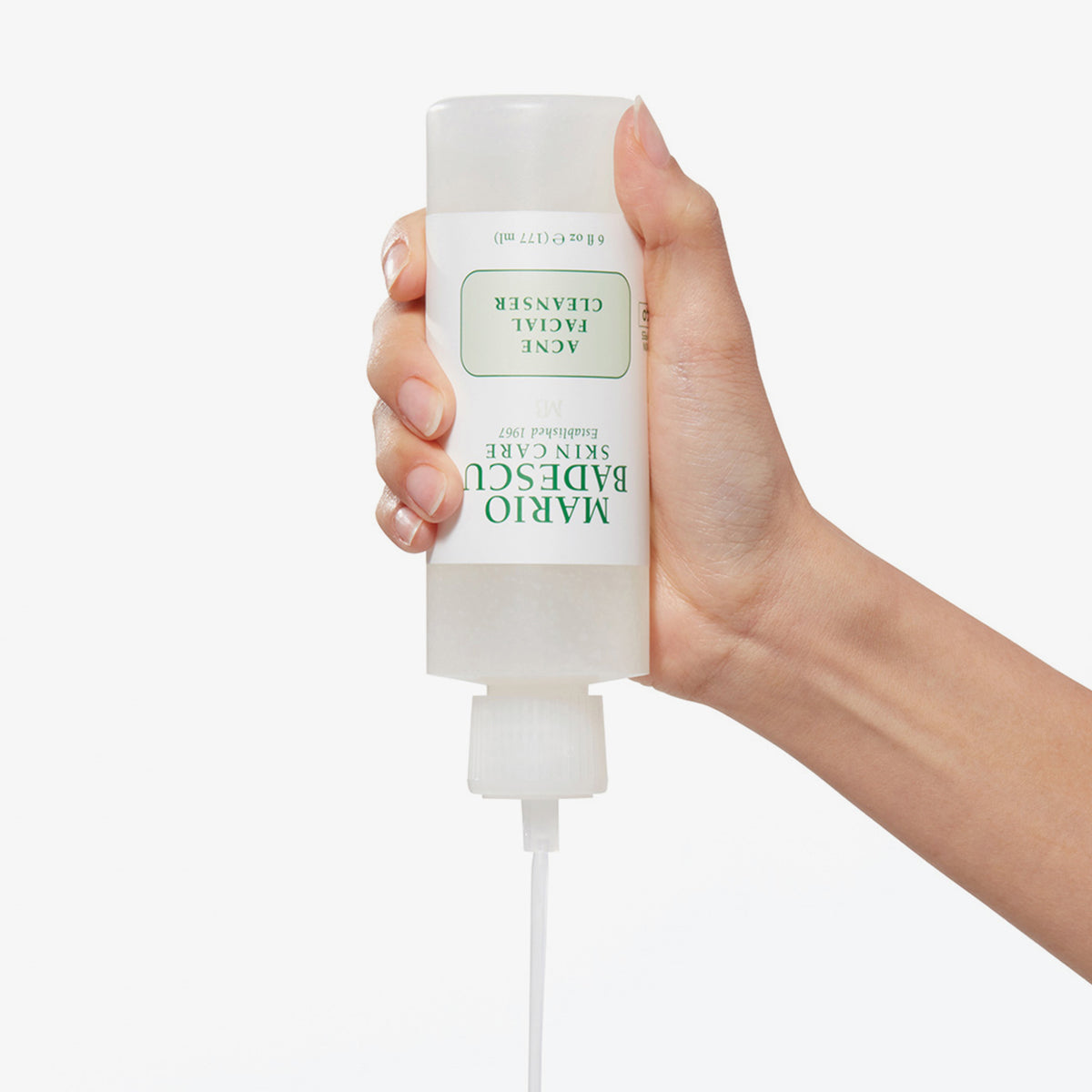 Eine Hand drückt die Flasche des Mario Badescu Acne Facial Cleanser zusammen und gibt den Reiniger aus der Düse frei.