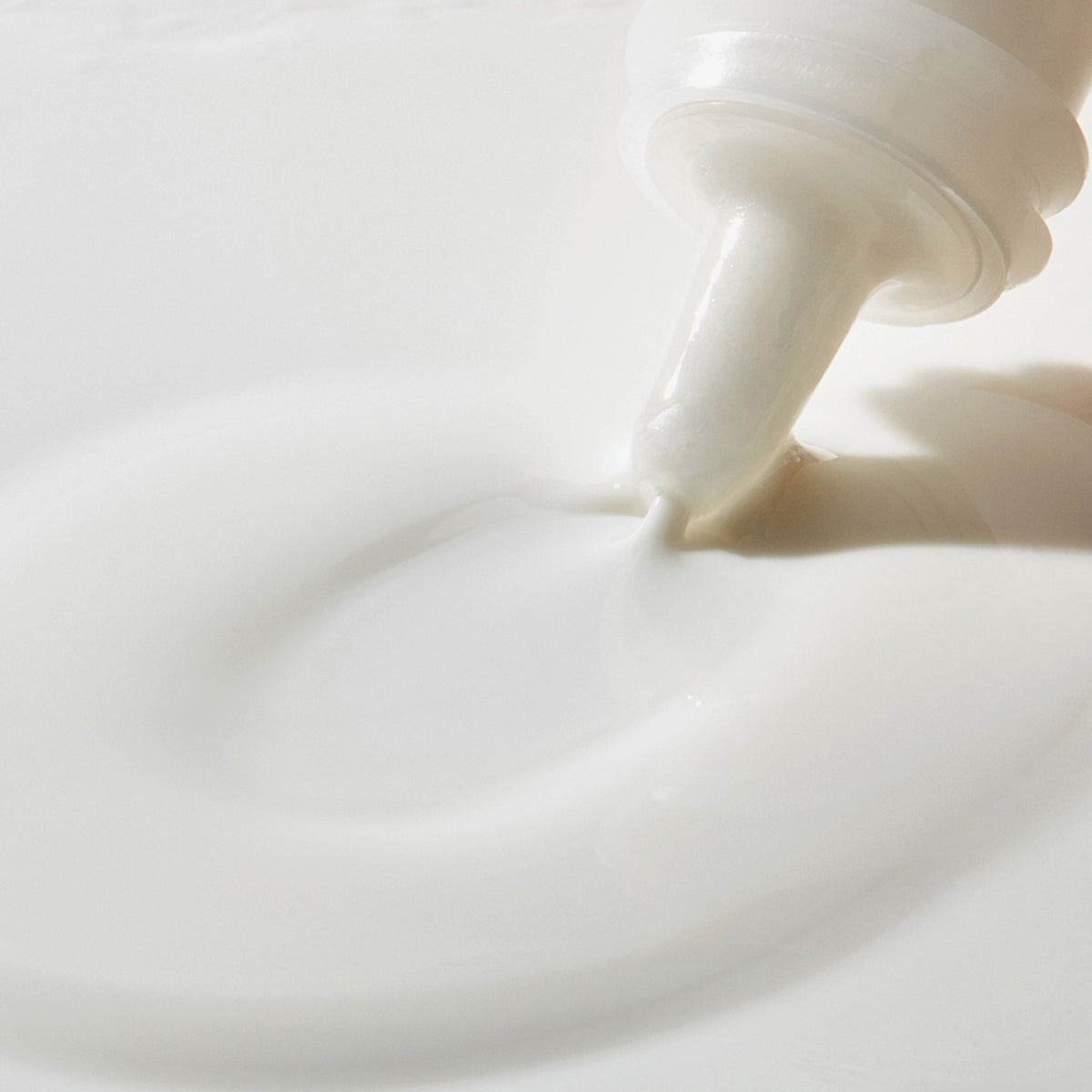Mario Badescu Buffering Lotion, die aus einer Tube auf eine glatte, weiße Oberfläche aufgetragen wird.