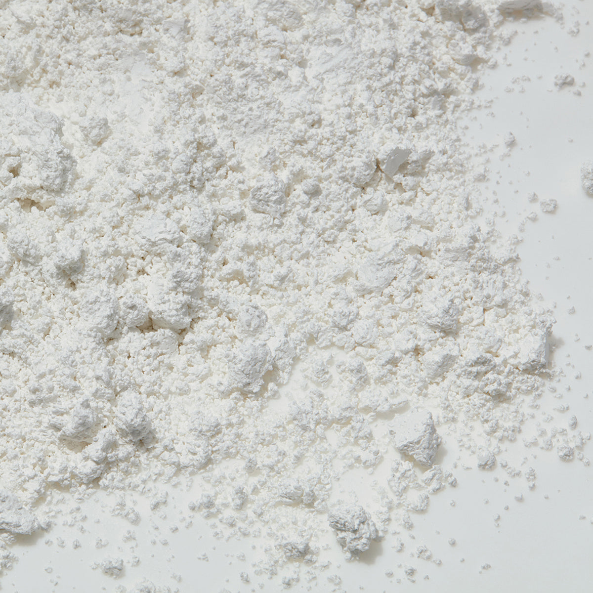 Der Pore Minimizer von Mario Badescu erscheint als weißes Pulver, das ungleichmäßig über eine glatte Oberfläche gestreut wird.