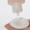 Eine Hand hält ein Wattepad, auf das Witch Hazel & Rosewater Toner aus einer Plastikflasche gegossen wird.