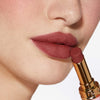 Nahaufnahme einer Person mit einem helleren Hautton, die sich den Beyond Blurry Lipstick, in der Farbe afrodite, auf die Lippen aufträgt.