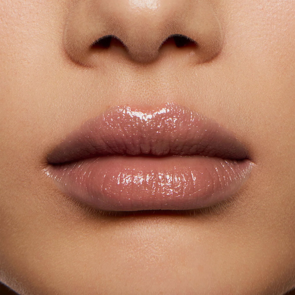 Nahaufnahme von glänzenden Lippen in Nude mit NABLA Cosmetics Beyond Jelly Lipstick Pearlescent auf glatter, heller Haut.