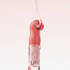 Nahaufnahme des Applikators vom Lip Candy oil über den Rosa Lipgloss fließt.