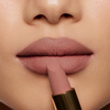Nahaufnahme von Lippen mit dem Nabla Cosmetics Matte Pleasure Lipstick in der Farbe Mauve Nude. Der Lippenstift wird an die Unterlippe gehalten.
