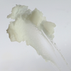 Ein Abstrich von NERDS. Centella-Reinigungsbalsam - eine dicke, weiße, cremige Substanz auf einer glatten, transparenten Oberfläche.