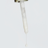 Eine Pipette gibt das NERDS. Hyperpigmentierung Serum - eine dicke, weiße Flüssigkeit - vor einem schlichten, hellen Hintergrund ab.