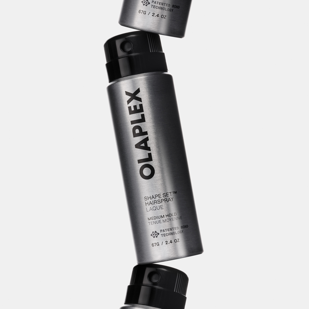 Drei zylindrische OLAPLEX Shape Set-Haarspray-Dosen, vertikal übereinander gestapelt.