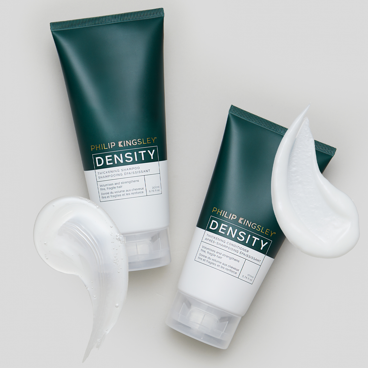 Zwei grüne Tuben „Philip Kingsley Density Thickening Conditioner“ mit weißen, durchsichtigen Wirbelmustern auf hellgrauem Hintergrund.