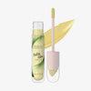 Eine geöffnete Tube Physicians Formula Butter Glow Corrector mit Applikator und einem Hauch cremigen Produkts im Hintergrund.