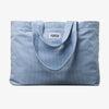 Die PURISH Beach Bag ist eine hellblaue Cordtasche mit Schultergurten und einem PURISH-Etikett auf der Vorderseite.