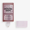Eine geöffnete Flasche Bright Light Bronzing Drops in Spice Tan/Deep mit Deckel daneben.