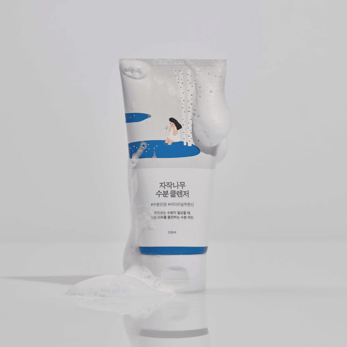 Runde Tube des Round Lab Birch Juice Cleansers mit schäumender Textur, blauer Illustration und koreanischem Text auf weißem Hintergrund.